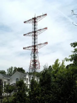 The Armstrong Tower at Alpine, New Jersey — a
                        tall red-and-white lattice broadcast tower with
                        three distinctive crossarms, rising above the
                        trees.