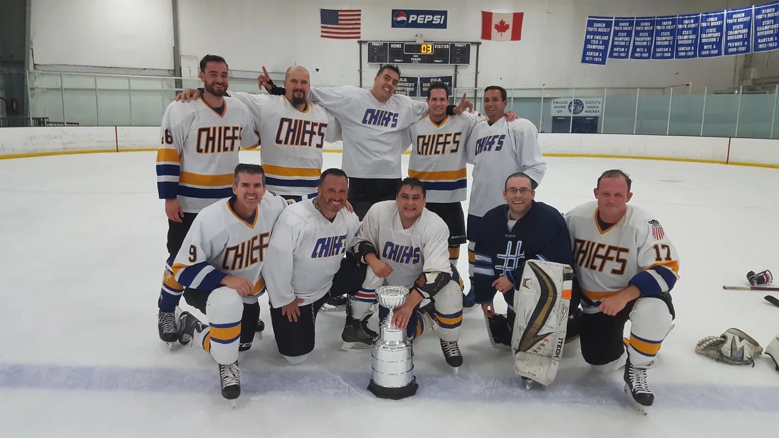 The Chiefs posed together on the rink ice around the
                  season cup trophy, celebrating after the
                  championship win.